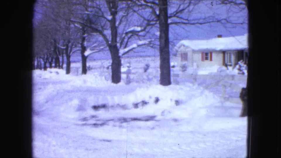 1963 Proctor, Minnesota frame with a plowed snowy road, bare roadside trees, and a house set back in winter light.
