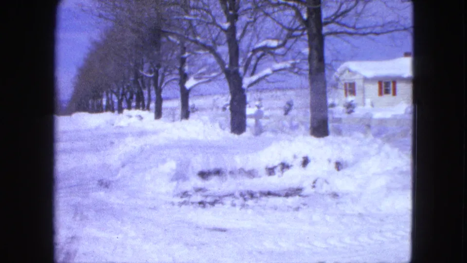 1963 Proctor, Minnesota 8mm frame showing bare trees, piled snow, and the edge of a modest house during a winter pan.