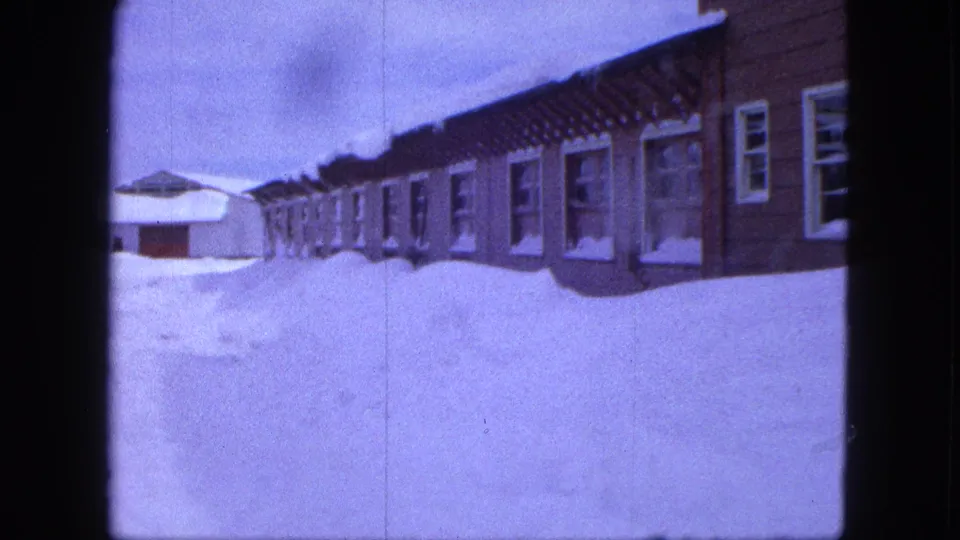 Snowbanks surround a row of Proctor, Minnesota houses in a purple-tinted 1963 8mm frame.