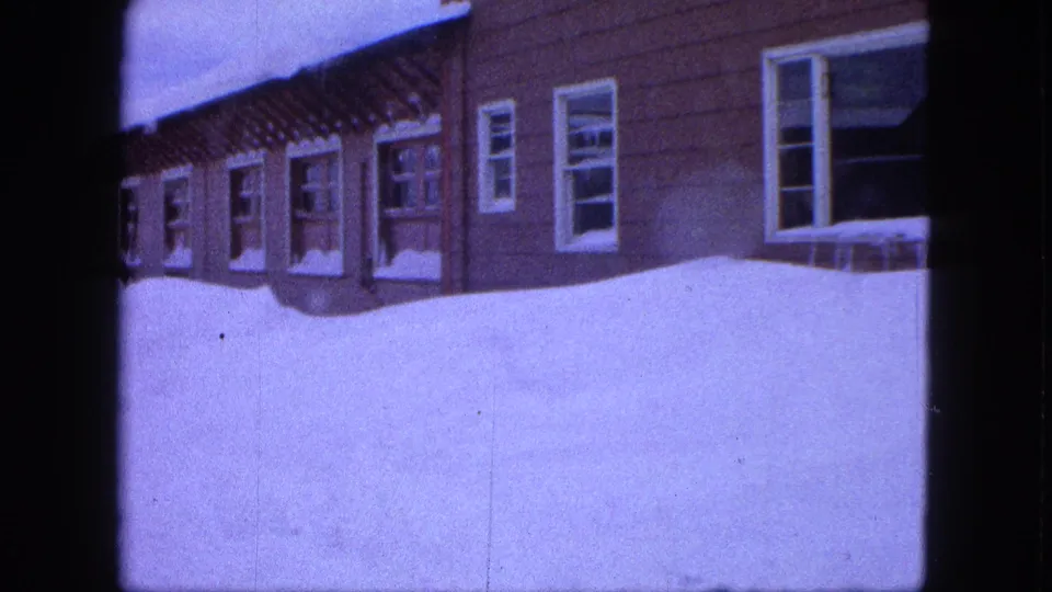Final frame shows Proctor houses and high snow cover with aged 8mm grain and color shift.