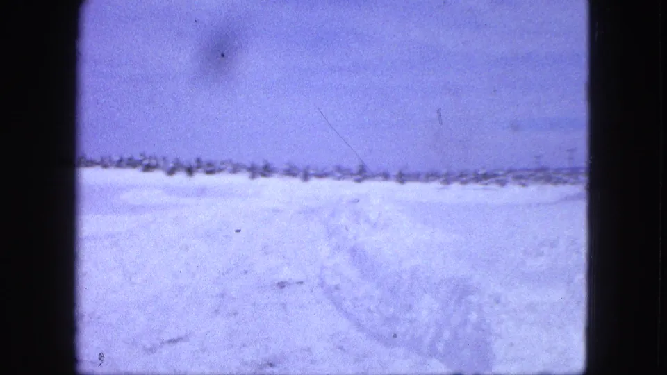 1963 8mm view of an open snow-covered field near Proctor, with faint tracks and a low horizon line.