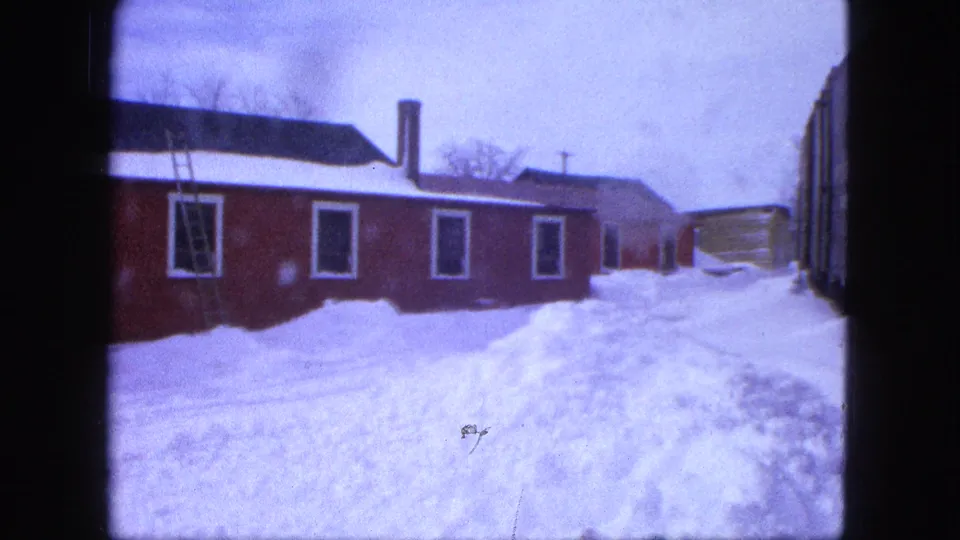 1963 Proctor, Minnesota frame of a red building with ladder, snowbanks, and rail equipment at the edge of the yard.