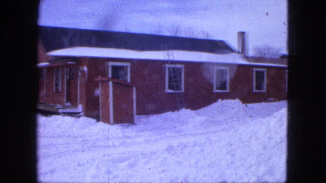 1963 Proctor, Minnesota winter frame with a red house, porch area, small shed, dark roof, and snow piled across the yard.