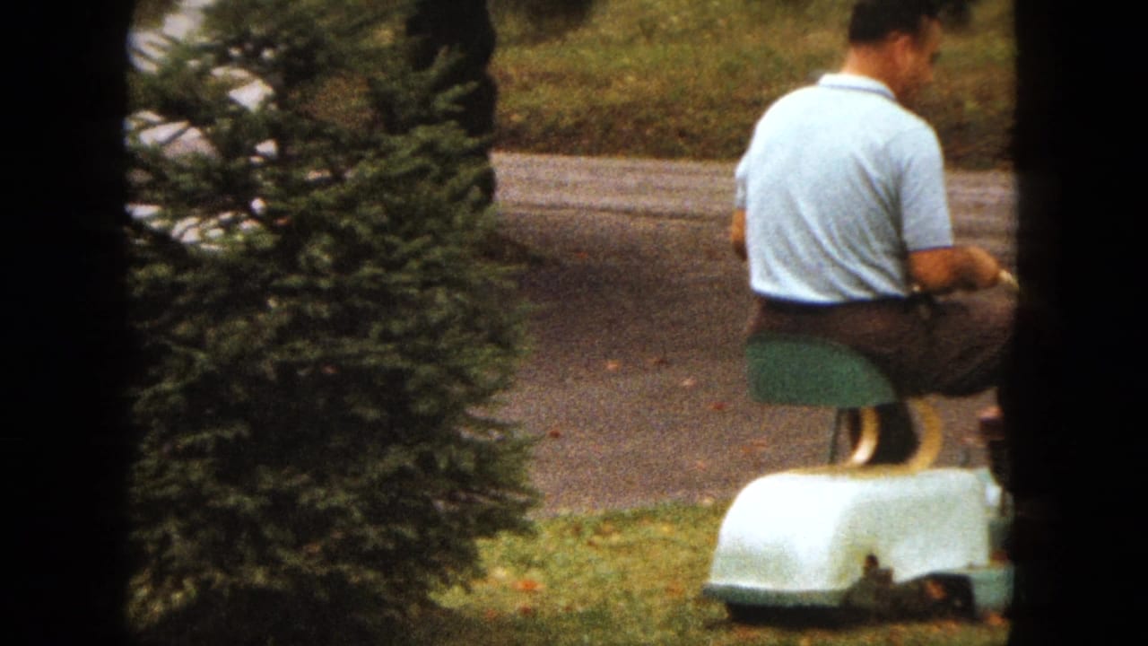 Man on a pale riding mower crosses a lawn, partly obscured by contact-sheet frame borders.