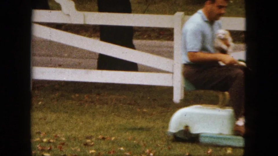 A 1963 Saint Paul yard scene shows the man seated on the mower with a puppy, framed by a white fence and grass.