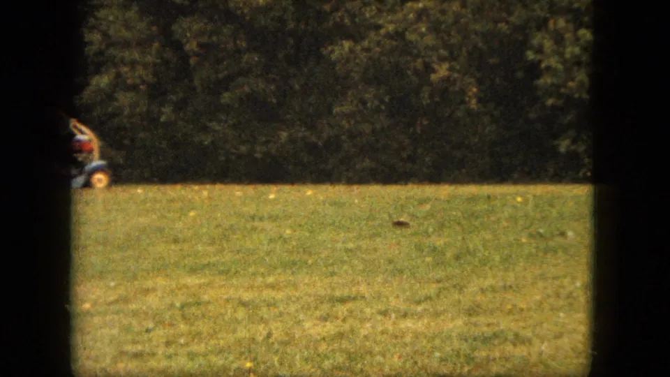 The 8mm frame catches part of the riding mower at the edge of a Saint Paul backyard lawn in 1963.