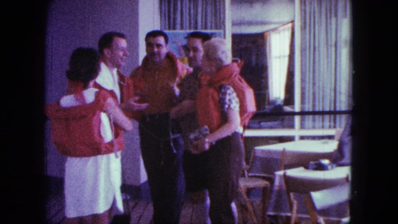 Five adults wearing red life jackets stand talking in a sunlit room with tables and curtains.