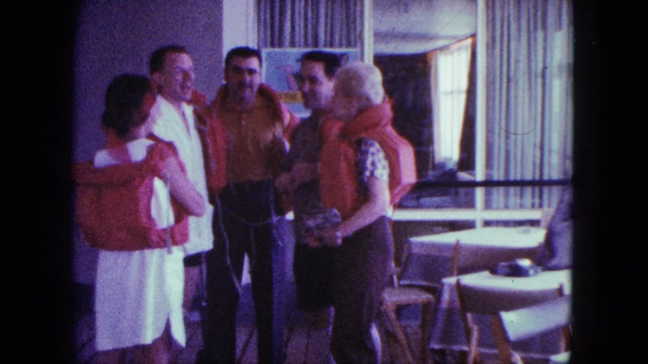 A group of adults in red life jackets smile and talk beside dining tables and tall curtains.