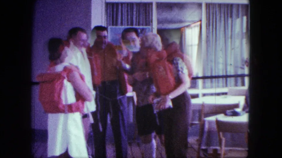 A home-movie frame from the San Diego clip shows adults in red life jackets conversing beside tables and tall curtained windows.