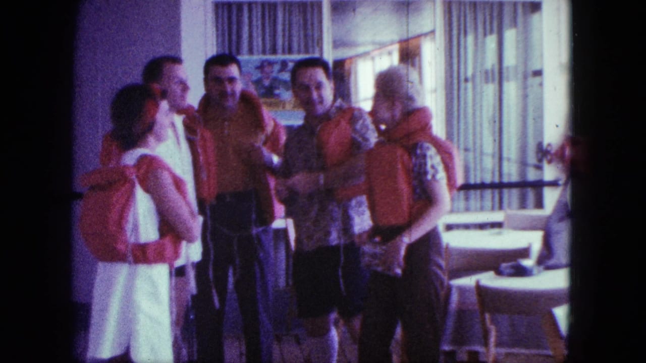 Five adults in orange life jackets stand together in a sunlit interior.