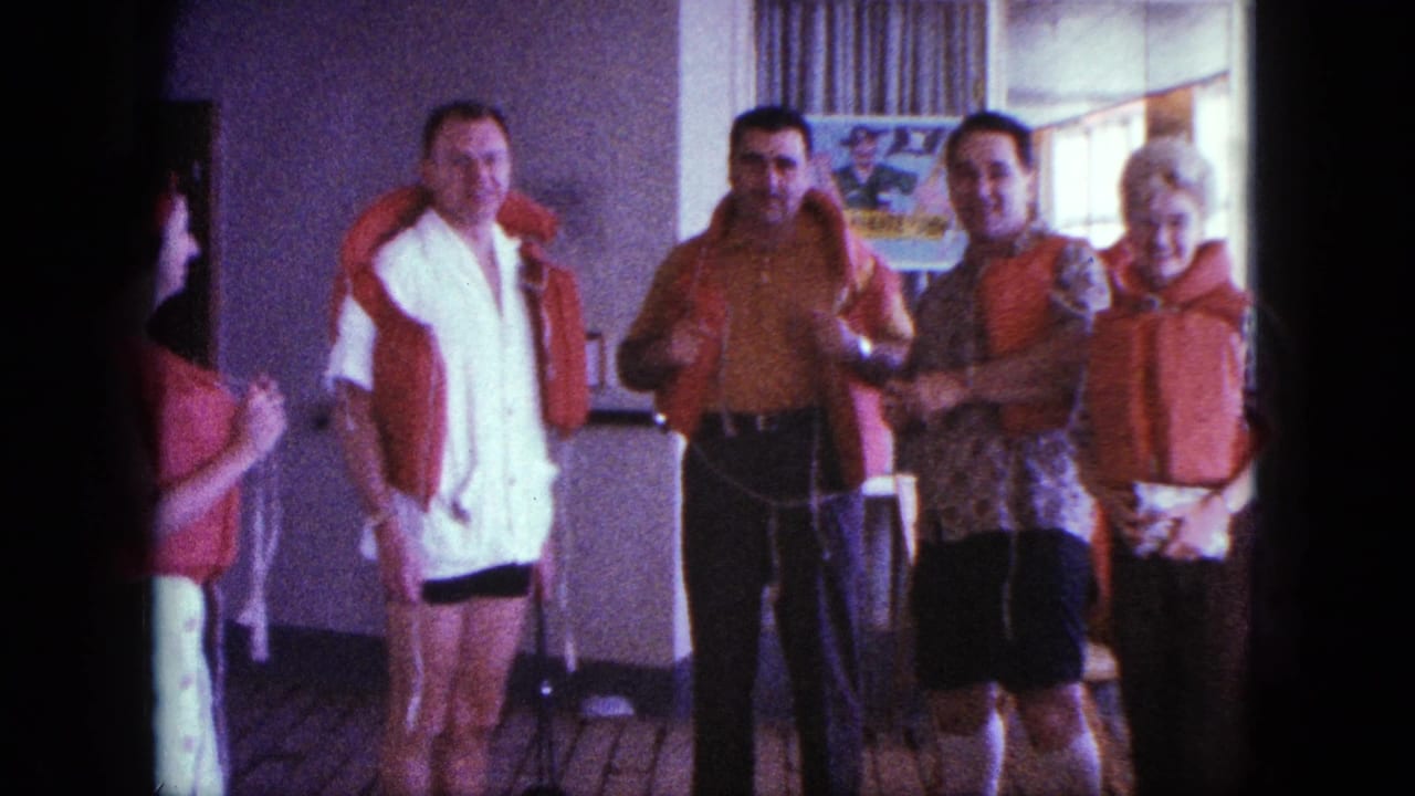 1963 San Diego home-movie frame of adults on a boat deck as orange life jackets are worn and adjusted during safety instruction.
