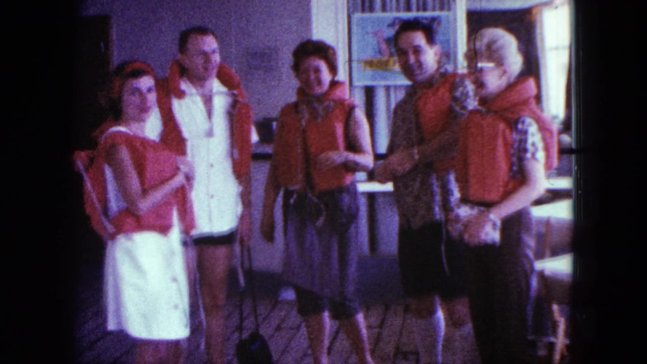 Five adults wearing red life jackets pose on a boat deck.