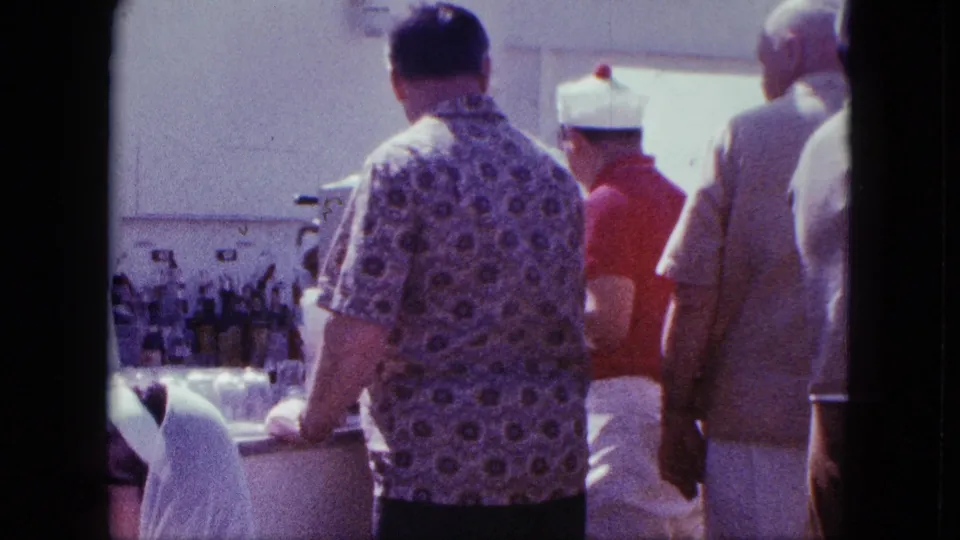 Home-movie view of adults at a San Diego outdoor refreshment counter in 1963, filmed from behind the line.