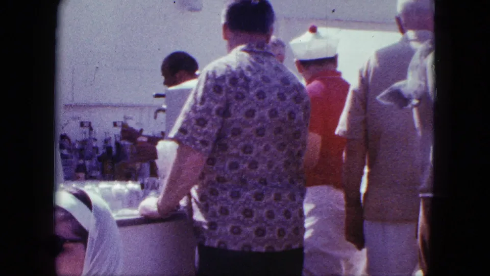 1963 San Diego 8mm frame of a busy outdoor concession counter with customers seen from behind and a vendor serving.