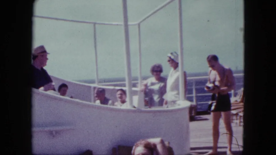 1963 San Diego cruise deck footage showing passengers in sunwear near white railings, with the ocean visible beyond the ship.