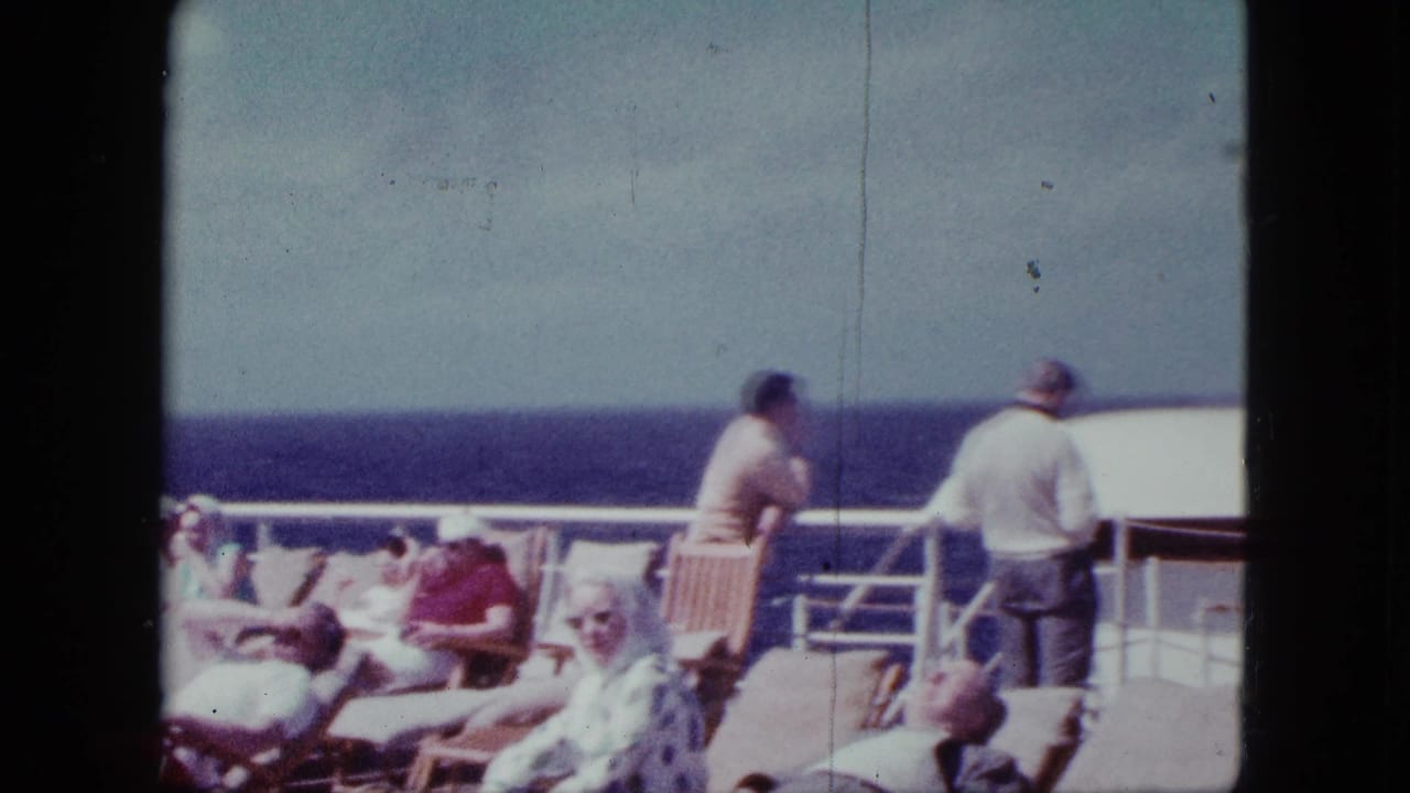 1963 cruise-deck view with seated and reclining passengers, two adults at the rail, and blue ocean beyond.
