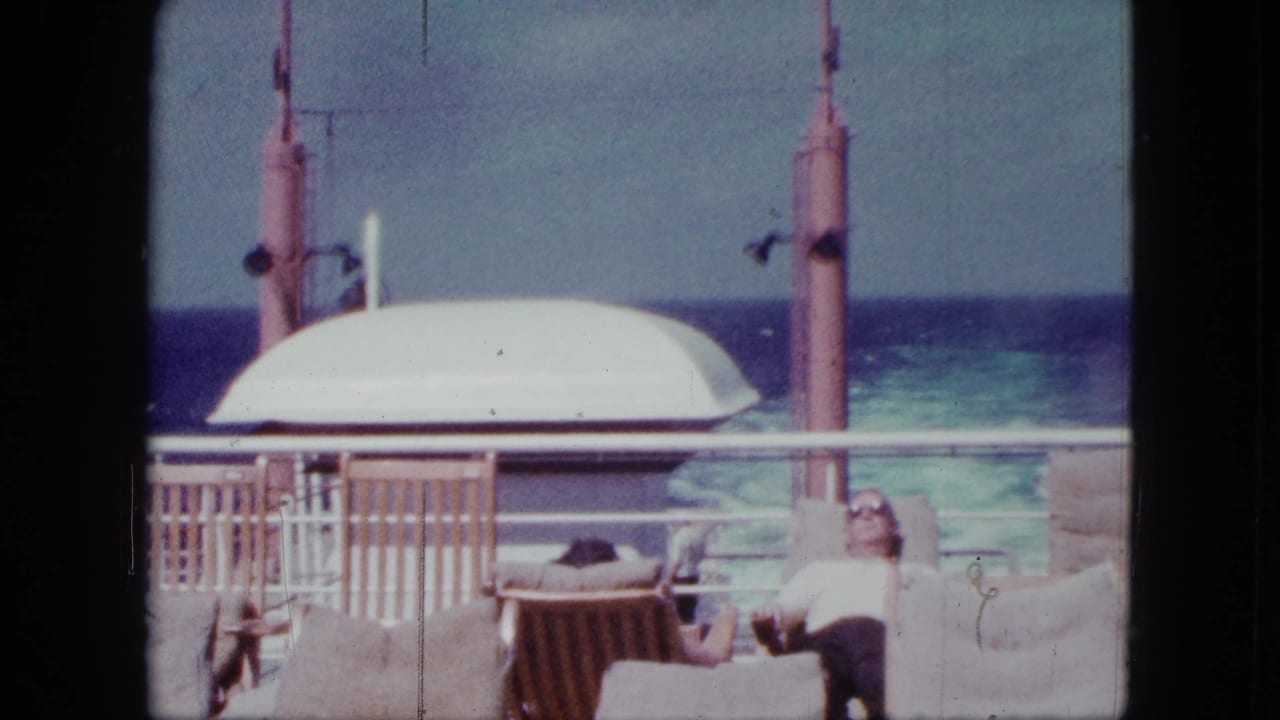 Passenger reclining on a ship deck with railing, lifeboat housing, and ocean behind.