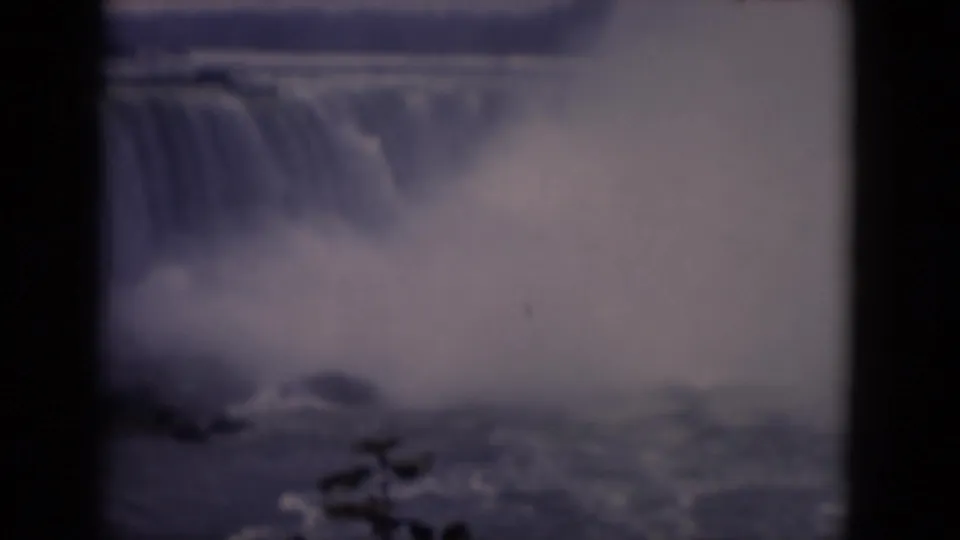 A 1964 8mm view of Horseshoe Falls with a visible curtain of water, heavy mist, and dark film-frame edges.