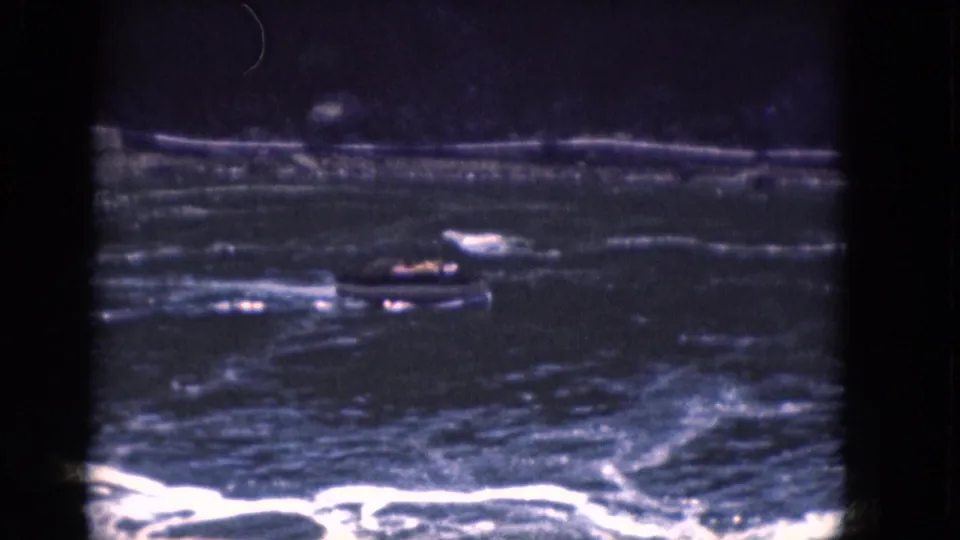 A small boat appears in turbulent Niagara River water below the falls, framed by dark edges and reflective rapids.