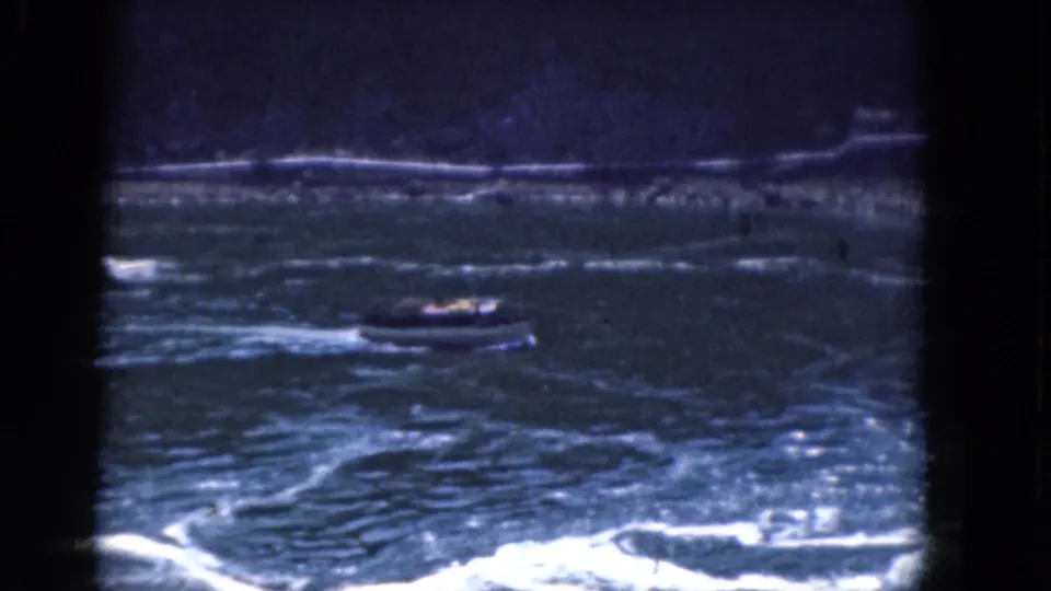 1964 Albany, New York 8mm frame showing a small motorboat low in the frame, surrounded by rough water and bright foam.