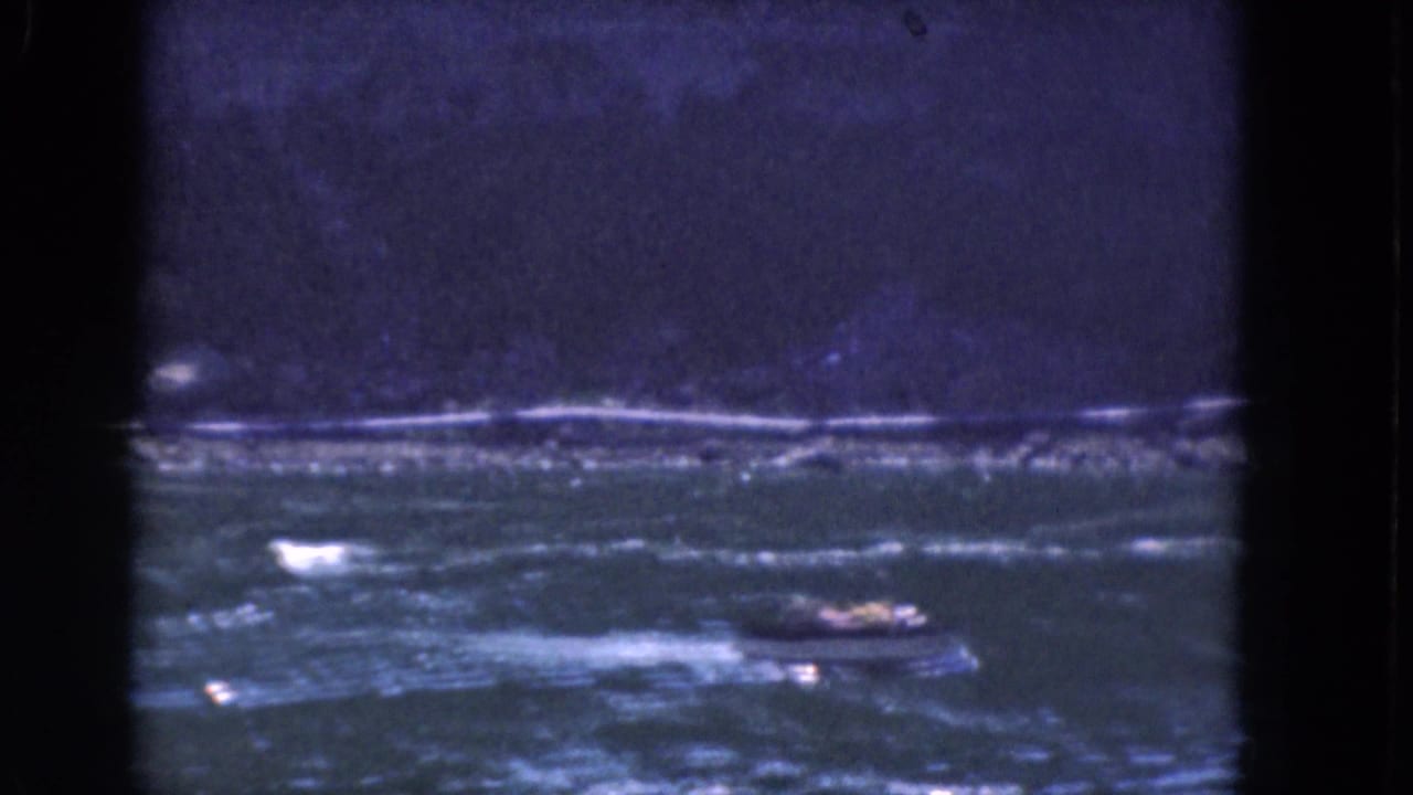 Motorboat farther across the river, leaving a pale wake under a dark horizon.