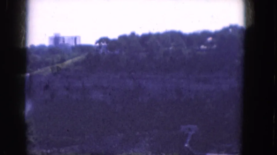 1964 Albany landscape frame showing a wooded hillside, a pale distant building, open foreground, and dark 8mm gate edges.