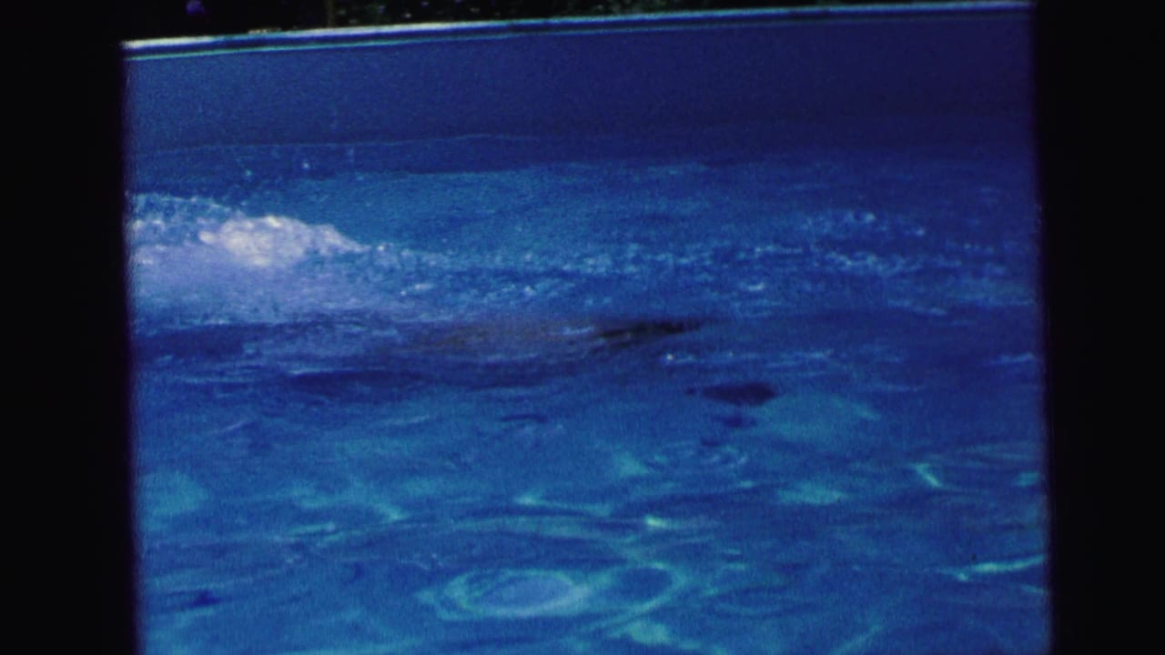 A swimmer is partly visible beneath reflective blue pool water in 1964 Camden, New Jersey home-movie footage.