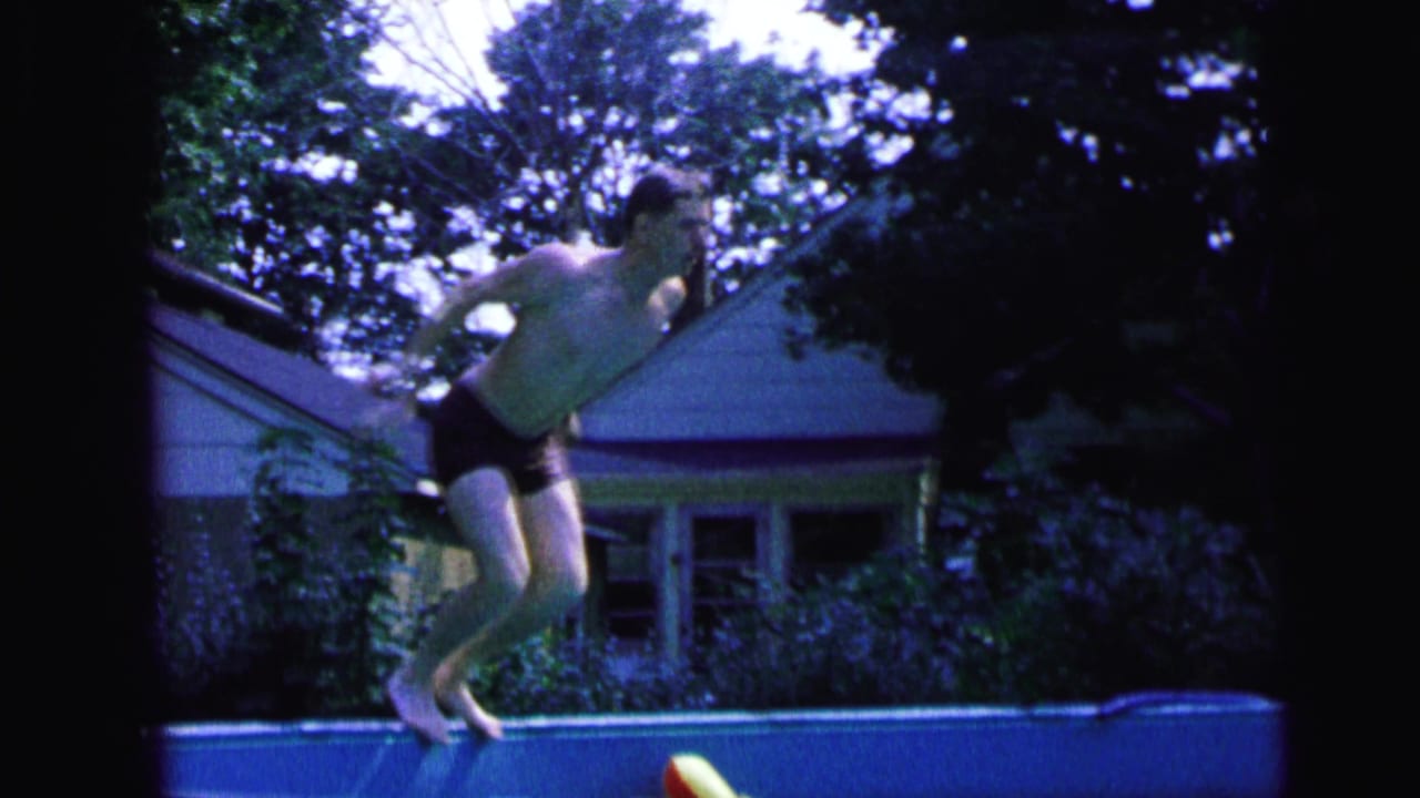 Young man bending forward at the pool edge before diving.