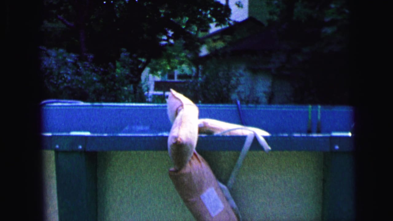 1964 Camden home-movie frame showing a pale life jacket or vest draped over the rim of an above-ground pool.