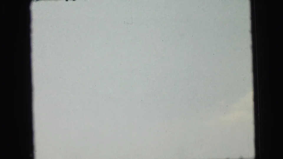 1964 Camden 8mm frame showing mostly pale sky with faint cloud coloration, dark vertical borders, and scattered film dust or scan marks.