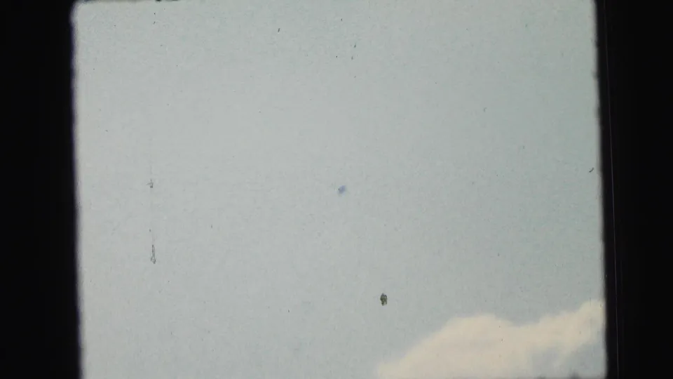 1964 8mm home-movie frame from Camden metadata showing pale sky, faint cloud, dust specks, and dark film borders.