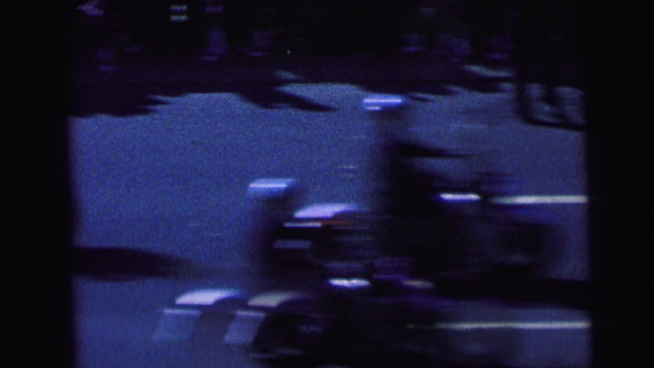 1964 Camden 8mm frame showing a dark, blurred nighttime road view with light streaks and a motorcycle-like form in motion.