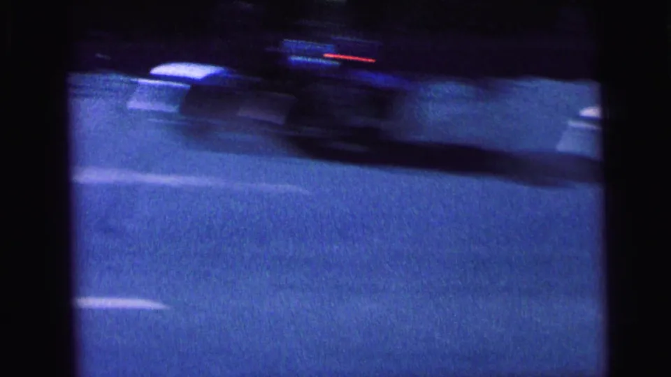 Fast-moving vehicle crosses a Camden, New Jersey street in 1964 8mm footage, with strong motion blur and blue-tinted exposure.