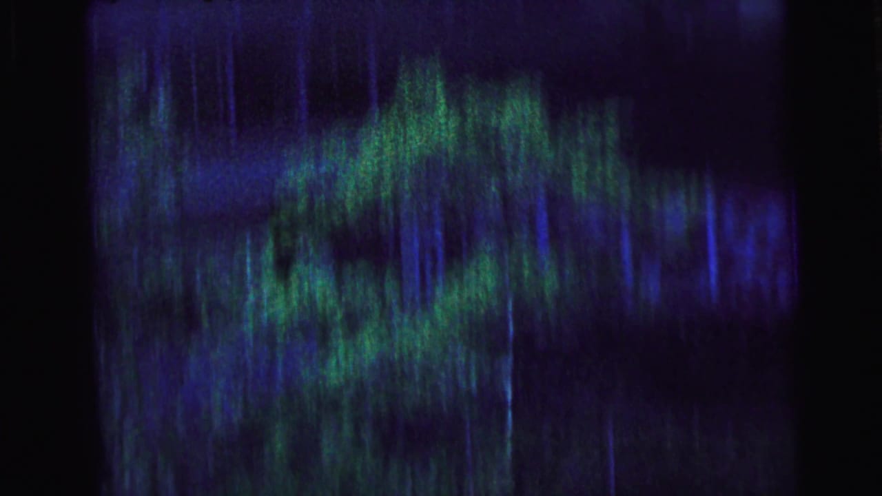 Abstracted 8mm frame from Camden, 1964, showing a screened view with blue-green blur before the motorcade becomes clear.