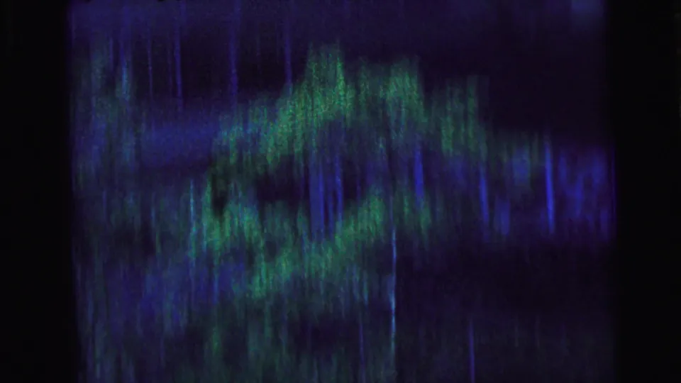 Abstracted 8mm frame from Camden, 1964, showing a screened view with blue-green blur before the motorcade becomes clear.
