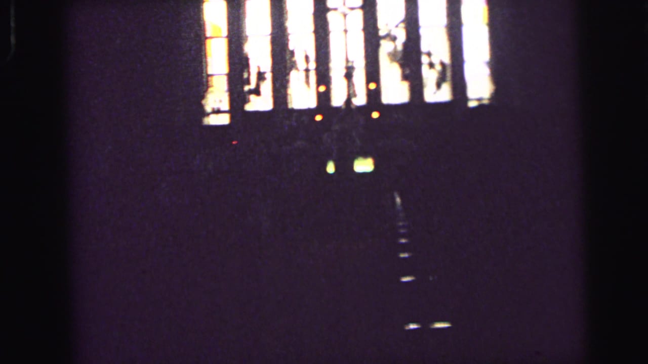 Dark church interior with bright stained-glass window panels and cross shapes.