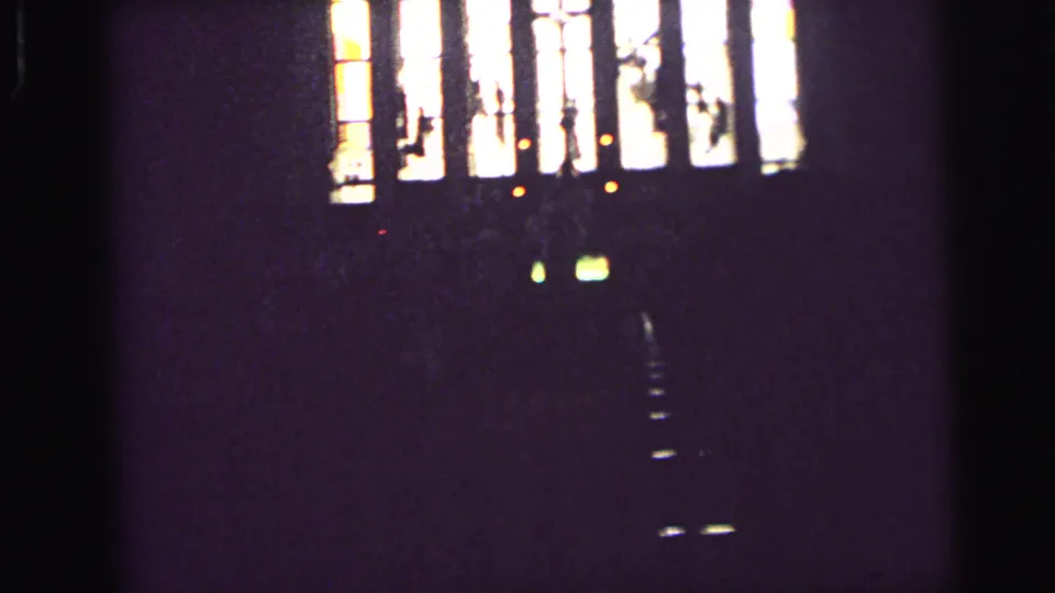 1964 Camden church interior view with bright stained-glass panels, cross forms, and deep surrounding shadow.