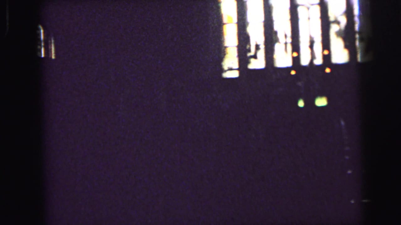 Stained-glass window partially framed by darkness inside a church.