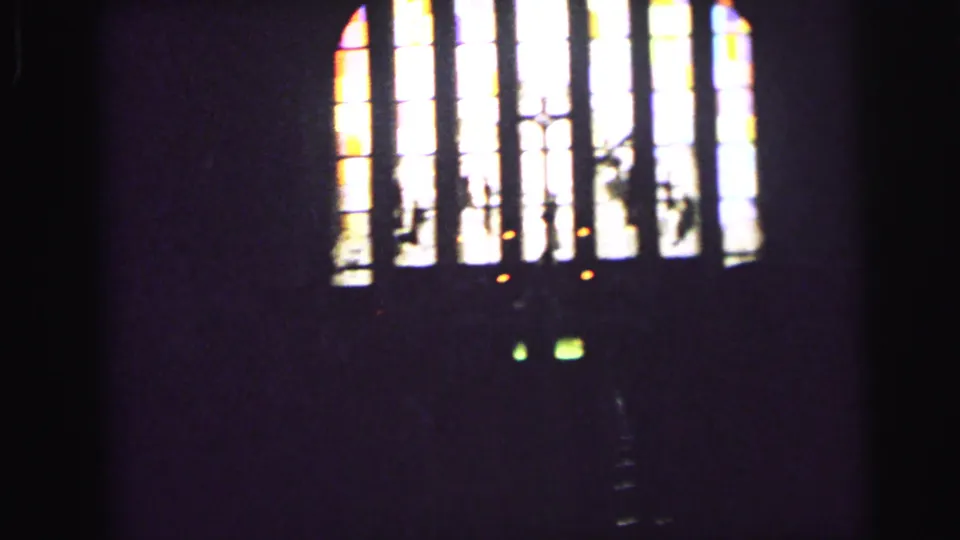 1964 Camden church view showing tall stained-glass panels, cross shapes, and dark interior space around the window.