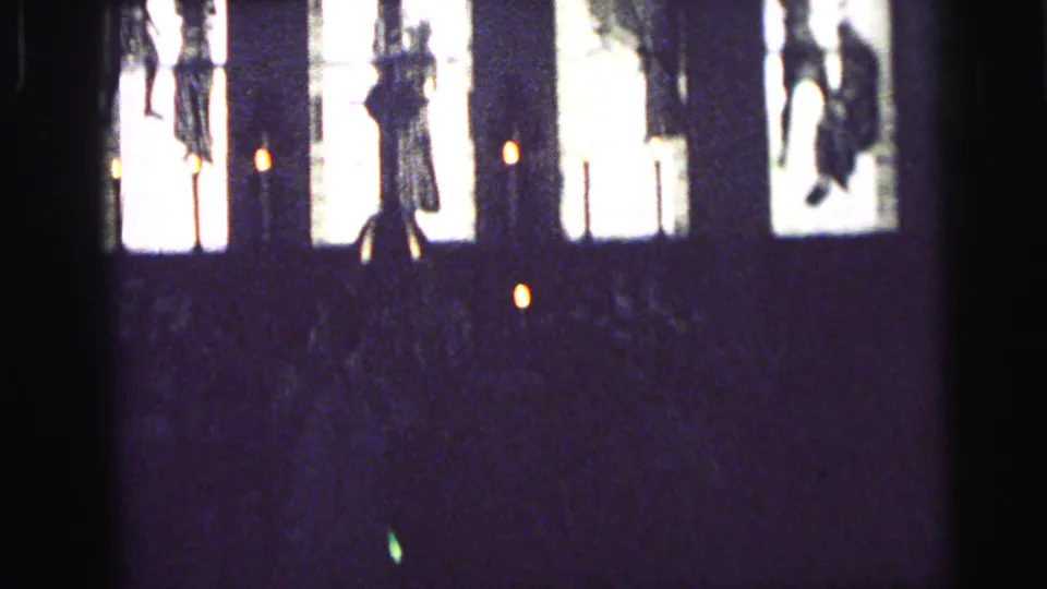 1964 church ceremony view in Camden with a cross and figures silhouetted against bright window light.