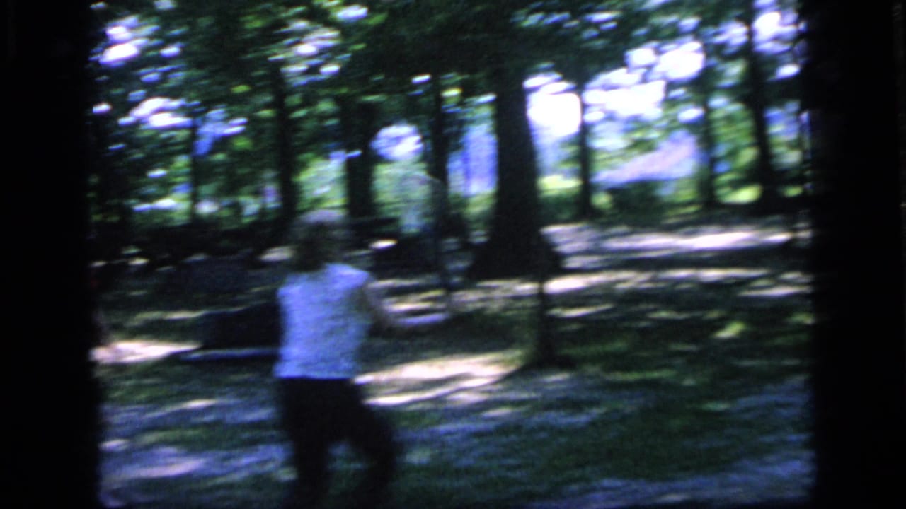 Woman seen from behind moves with a racket among trees.