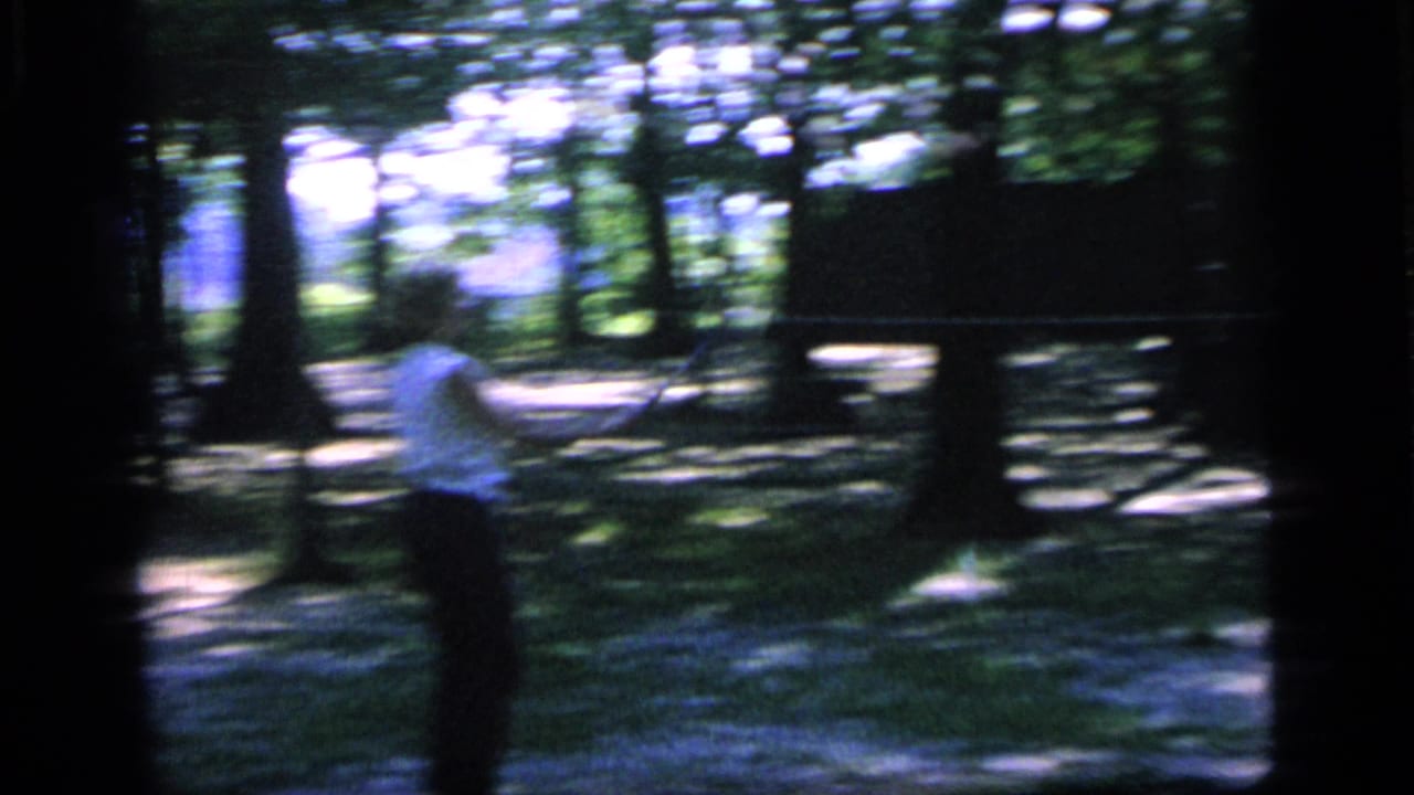 Blurred handheld view of the woman moving through trees during the badminton game.