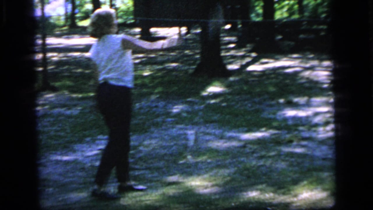 In Camden, New Jersey, 1964, a woman in casual clothing prepares to play badminton among trees and dappled sunlight.