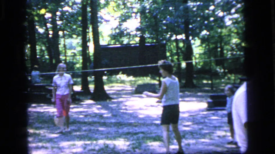 Several people gather near a badminton net in Camden, New Jersey, during an informal 1964 park game.