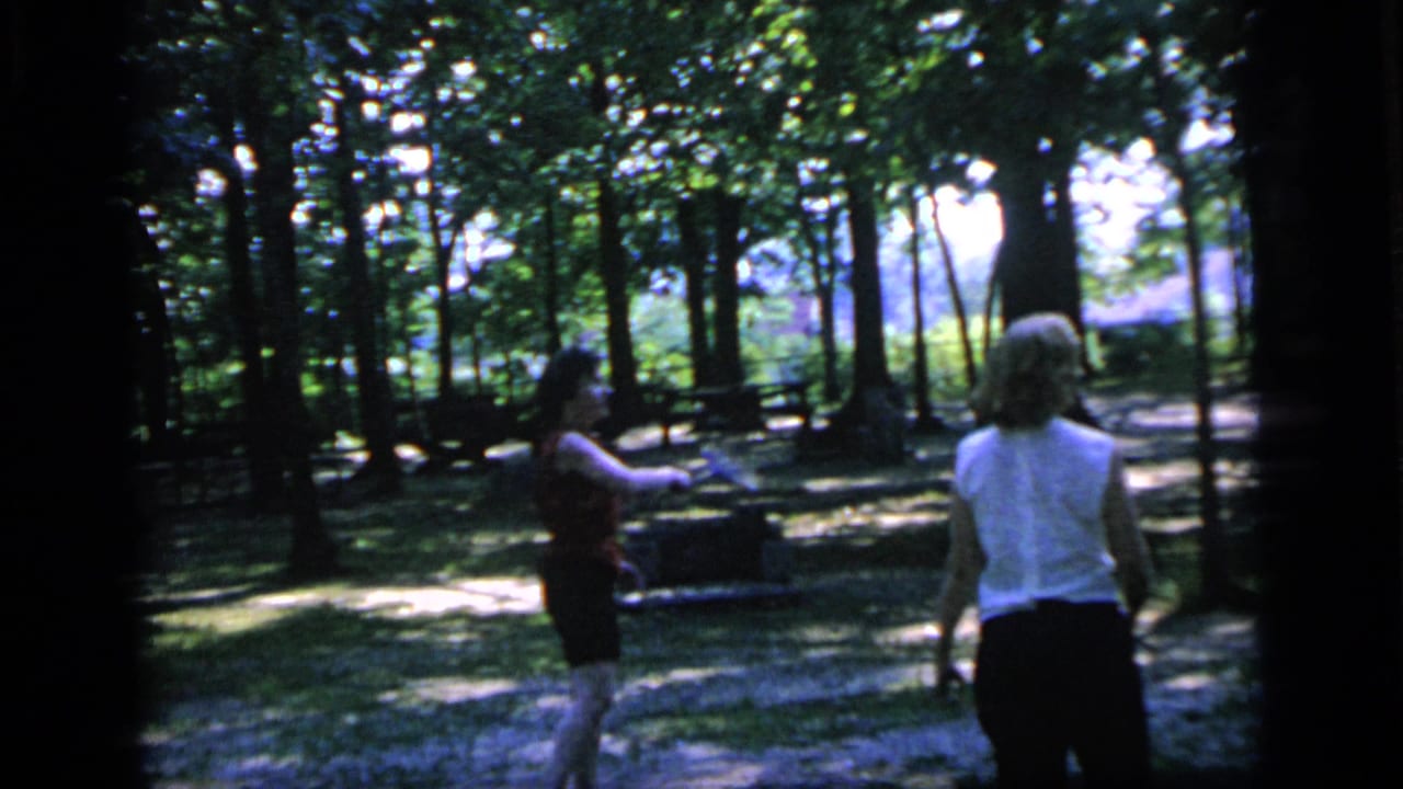 Two women play badminton in a tree-filled Camden, New Jersey park in 1964, seen in soft 8mm home-movie color.
