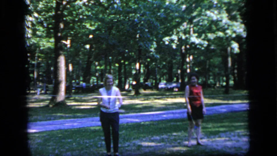 The badminton players remain on the grass in the wooded Camden park, framed by the dark edges of the 8mm scan.