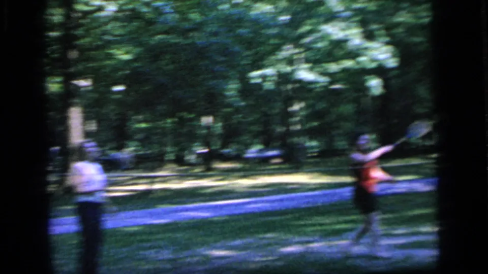 1964 Camden park footage shows a woman in red swinging a racket while another woman stands near the path.