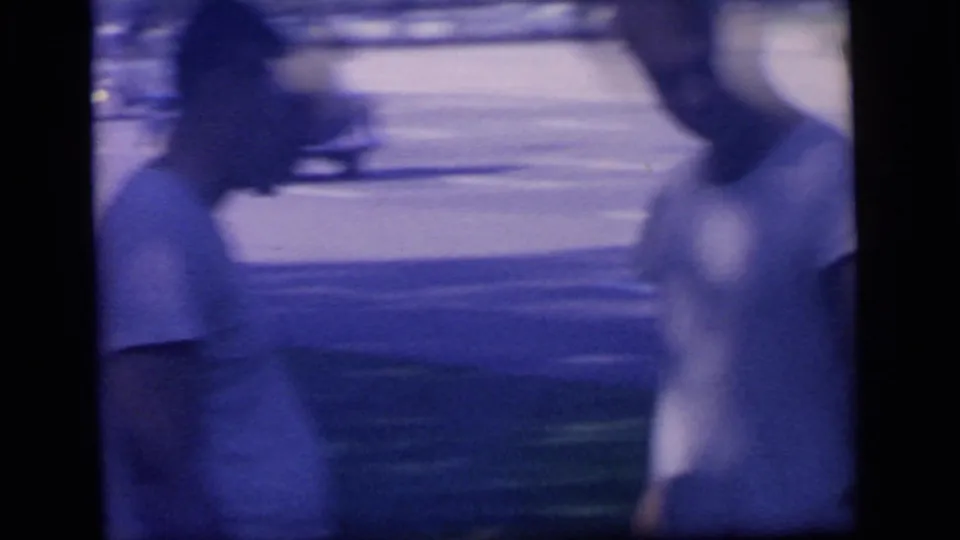 A motion-blurred close view shows the man in a white T-shirt moving past the handheld camera near the park road.