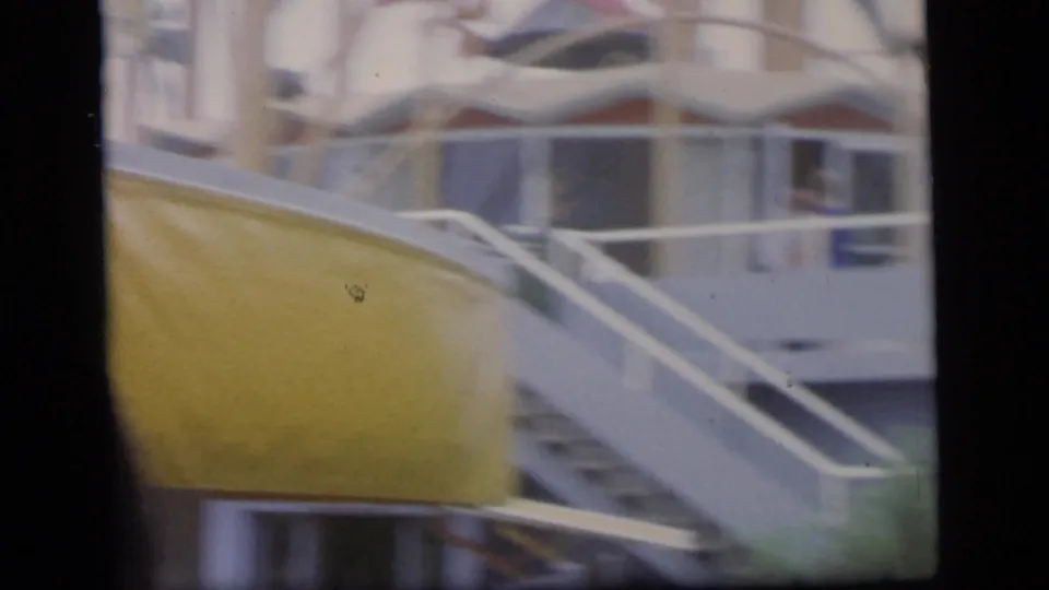 Soft 1964 8mm frame in Camden showing a blurred yellow structure, pale railings, and an indistinct foreground head.