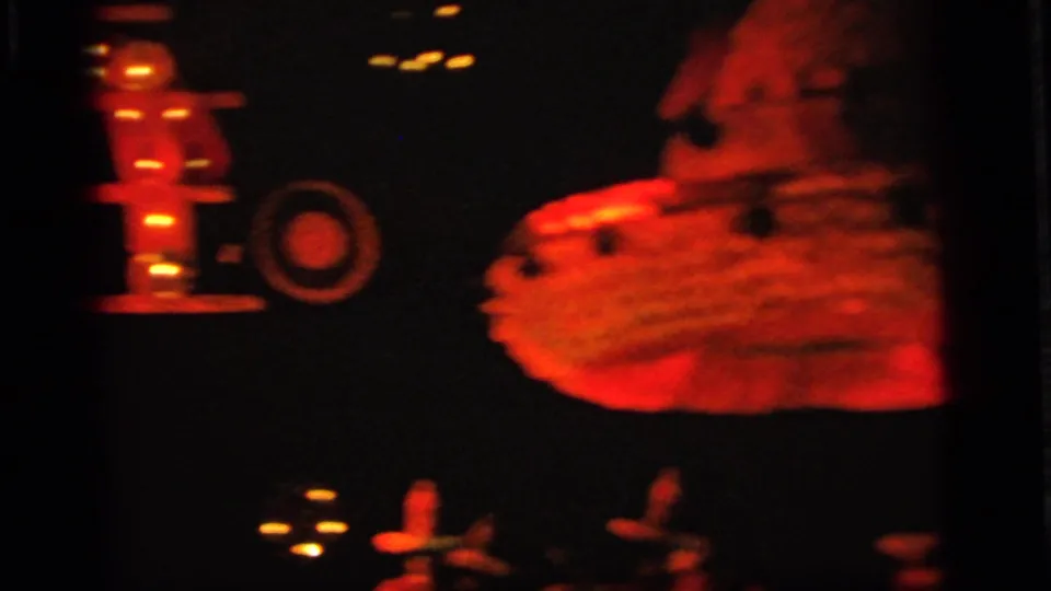 1964 Camden, New Jersey 8mm frame showing red-lit toy-like forms and small lights in a dark amusement display.